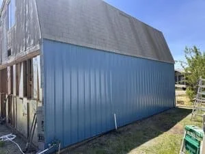 Blue corrugated metal building addition with vertical siding and pitched roof