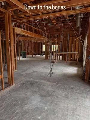 Interior framing with wood studs, electrical wiring, and concrete floor in residential remodel