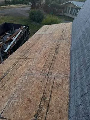 OSB roof decking installation with fasteners and gray roofing material visible at edge