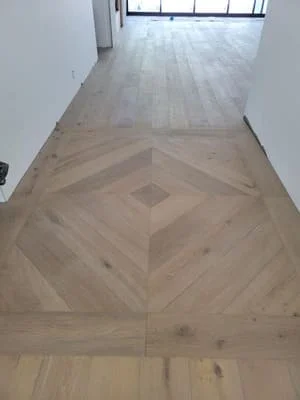Light oak hardwood flooring with geometric diamond inlay pattern in hallway