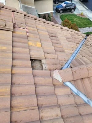 Roof repair in progress showing removed clay tiles and new gutter installation on residential home