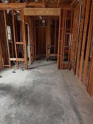 Interior framing with wooden studs, doorways, and concrete subfloor in residential remodel