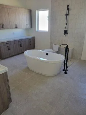 Modern master bathroom with white freestanding tub and gray wood vanity cabinetry