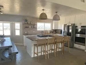 Modern kitchen with white island, stainless steel appliances, and polished concrete floors