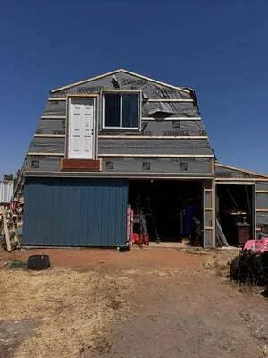 Barn structure renovation with new metal siding, white entry door, and window installation