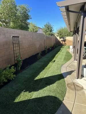 Newly landscaped backyard with green sod, concrete patio, and privacy fence in Temecula
