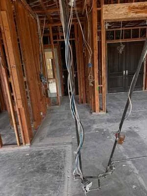 Interior framing with wooden studs, electrical conduit, and concrete floor during construction phase