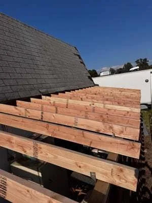 New roof framing with dimensional lumber joists installed over existing shingle roof