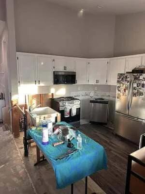 Modern kitchen with white cabinets, stainless steel appliances, and dark wood floors