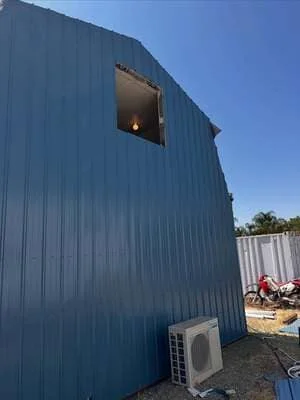 Blue metal building with sloped roof and exterior HVAC unit installation